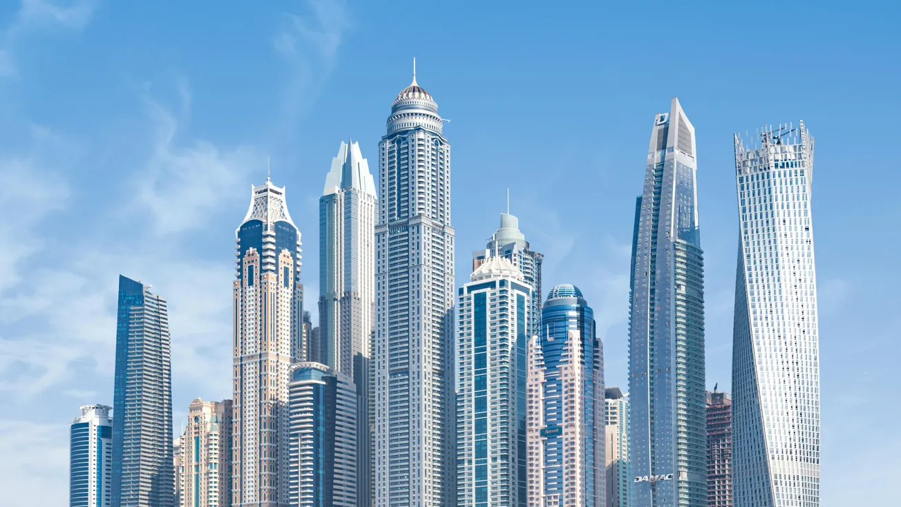 A skyline of tall, modern skyscrapers against a clear blue sky, showcasing various architectural designs, conveying a sense of innovation and grandeur.